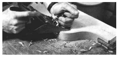 Jere handplanes the edge of the veneers while it is clamped to one side of the form, using it as a guide for when to stop planing.